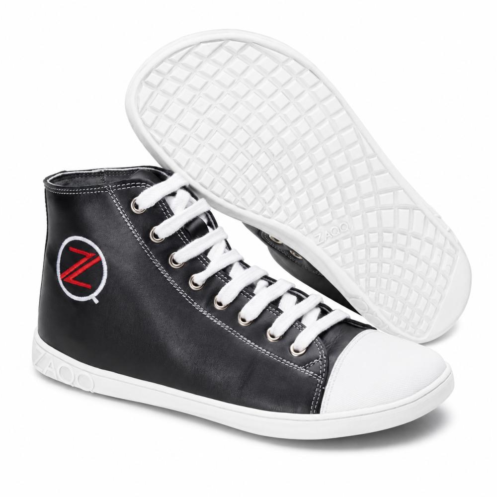 Les baskets montantes noires CHUQQS de ZAQQ ont des semelles et des lacets blancs, renforcés par un embout blanc. Sur le côté, un logo avec un Z rouge dans un cercle blanc est visible. La semelle en caoutchouc est conçue avec un motif en grille pour une meilleure adhérence et durabilité.