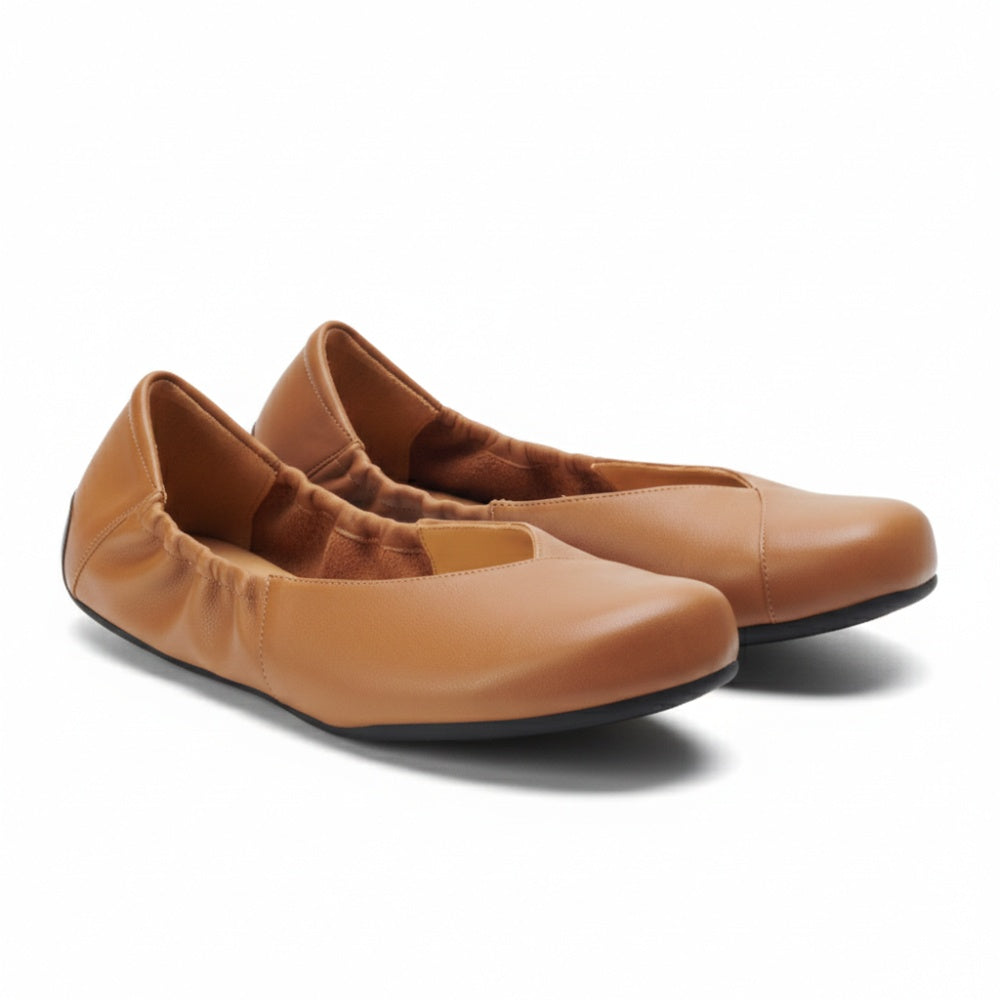 Ein Paar braune ZAQQ MAIQA Ballerinas mit elastischen Seiten und abgerundeten Zehen, von der Seite präsentiert. Die Schuhe haben eine glatte Textur und schwarze Sohlen, die eine flexible Sohle bieten, die ideal für Komfort und lässiges Tragen ist.