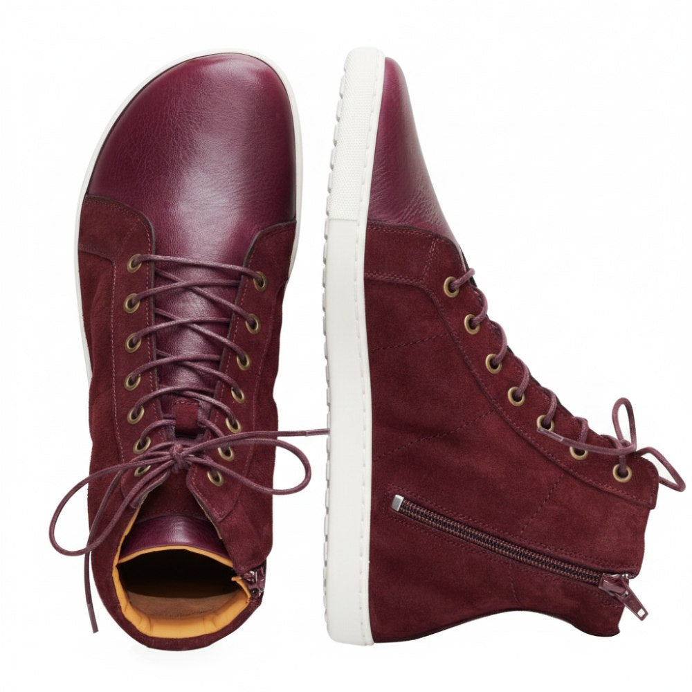 Präsentiert werden die Schuhe QORE High Mazarine in Kastanienbraun, einer steht aufrecht, der andere ist flach. Diese halbhohen Sneaker von ZAQQ sind aus Velours- und Glattleder gefertigt, haben seitliche Reißverschlüsse und eine strukturierte Sohle, die stolz das Markenlogo zeigt.