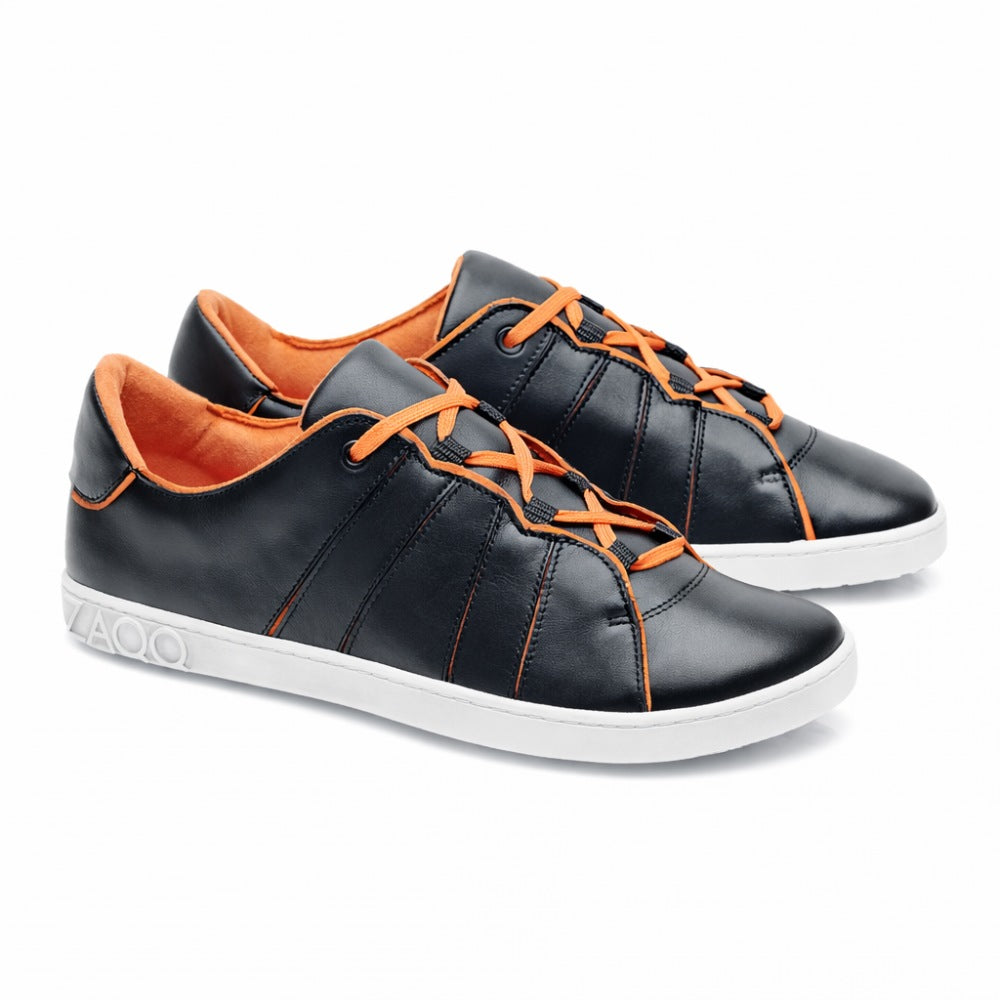 Ein Paar schicke QQQ Low Black Orange Sneaker von ZAQQ, mit leuchtend orangefarbenen Schnürsenkeln und Innenfutter. Die Schuhe bestechen durch veganes Futter und eine weiße Sohle mit kreisförmigem Muster in Fersennähe. Schräg positioniert, zeigen sie ihr stylisches Design.