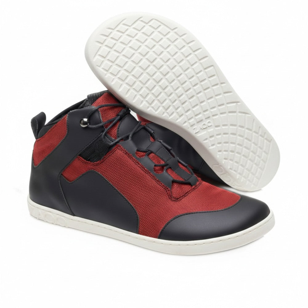 Wir präsentieren die RAQO Black Red High-Tops von ZAQQ. Dieser moderne vegane Sneaker zeichnet sich durch eine auffällige Kombination aus rotem Stoff und schwarzem lederähnlichem Material aus. Die Sohlen sind grau mit einem komplizierten strukturierten Gittermuster. Ein Schuh liegt auf der Seite, um die Sohle hervorzuheben, während der andere hoch steht, um sein stilvolles Design zu präsentieren.