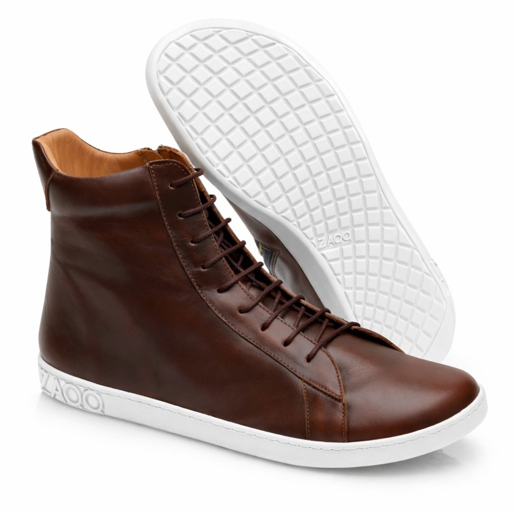 Ein Paar SNAQ Antique Brown High-Top-Sneaker mit weißer Sohle, hergestellt von ZAQQ. Ein Schuh steht aufrecht, während der andere geneigt ist, sodass die Sohle mit Waffelmuster sichtbar ist. Die stylischen Barfußschuh-Sneaker sind an der Seite mit dem ZAQQ-Logo verziert.